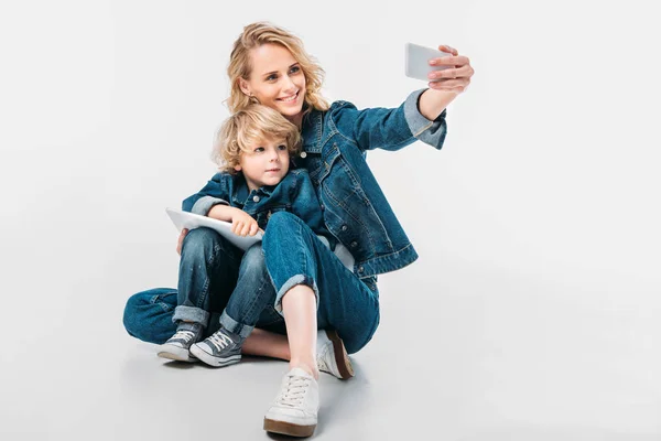 Mutter und Sohn machen Selfie mit Smartphone auf Weiß — Stockfoto