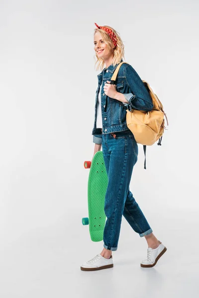 Attraente donna a piedi con borsa e skateboard isolato su bianco — Foto stock