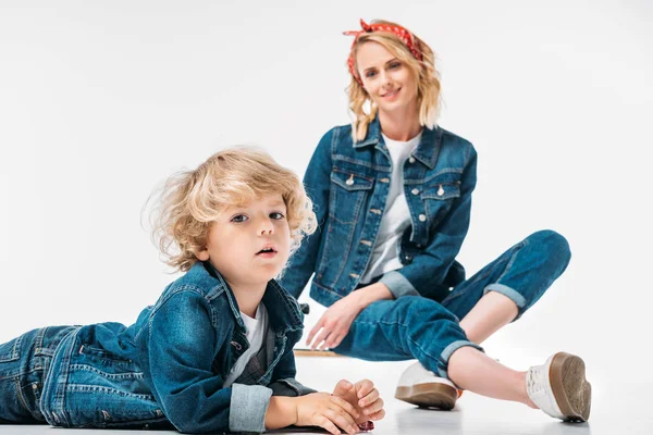 Mother sitting on skateboard and looking at son on white — Stock Photo