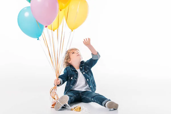 Entzückender Junge erreicht Bündel von Luftballons mit Hand isoliert auf weiß — Stockfoto
