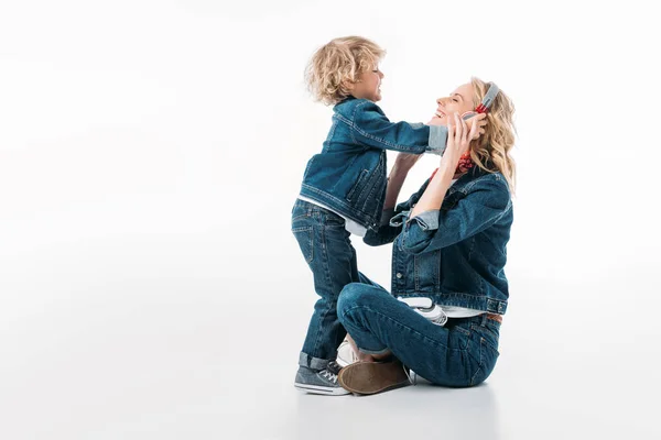 Son wearing headphones on mother to listen to music on white — Stock Photo