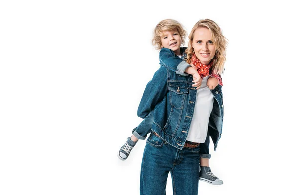 Sonriente madre divirtiéndose y dando piggyback a hijo aislado en blanco - foto de stock