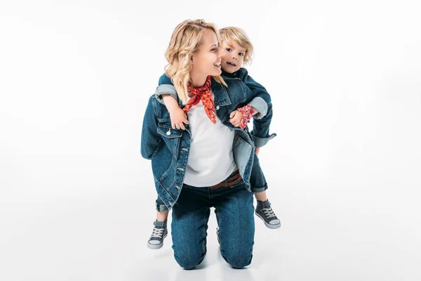 Glückliche Mutter gibt Sohn Huckepack auf Weiß — Stockfoto