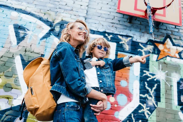 Low angle view of mother holding son and he pointing on something on street — Stock Photo