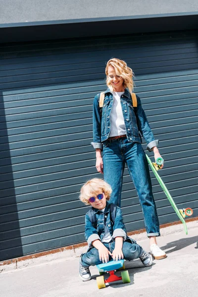 Sorridente madre e figlio con longboard in strada — Foto stock