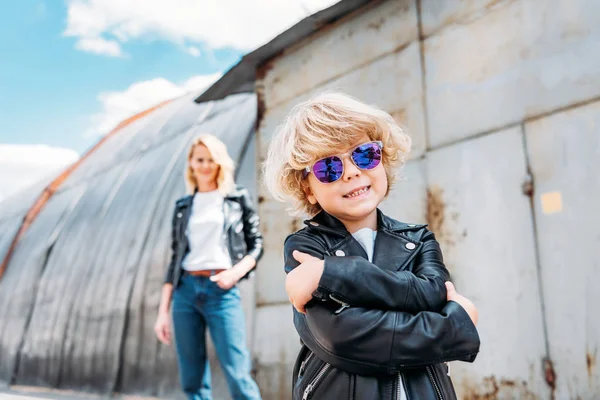Stylish son in sunglasses standing with crossed arms on street — Stock Photo
