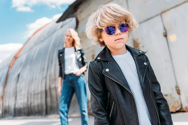 Fils élégant en vêtements décontractés et lunettes de soleil marchant dans la rue — Photo de stock