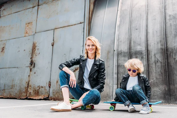 Mother and son sitting on skateboards on street — Stock Photo