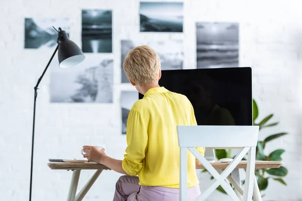 Rückansicht einer Geschäftsfrau, die Kaffee trinkt und am Computer am Tisch arbeitet — Stockfoto