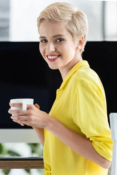 Портрет счастливой женщины фрилансер держа чашку кофе за столом с компьютером — стоковое фото