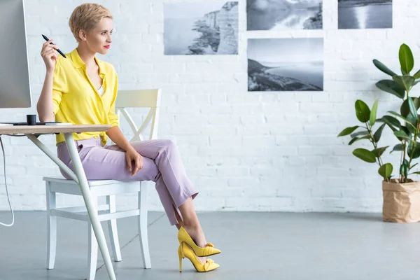 Femme indépendante réfléchie assise à table avec ordinateur au bureau à la maison — Photo de stock