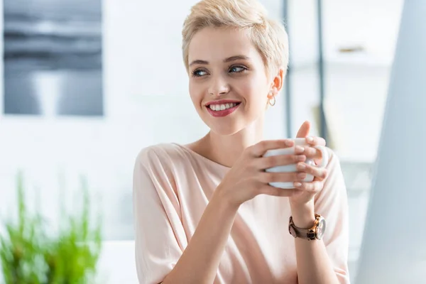 Portrait de femme tenant une tasse de café et regardant loin — Photo de stock