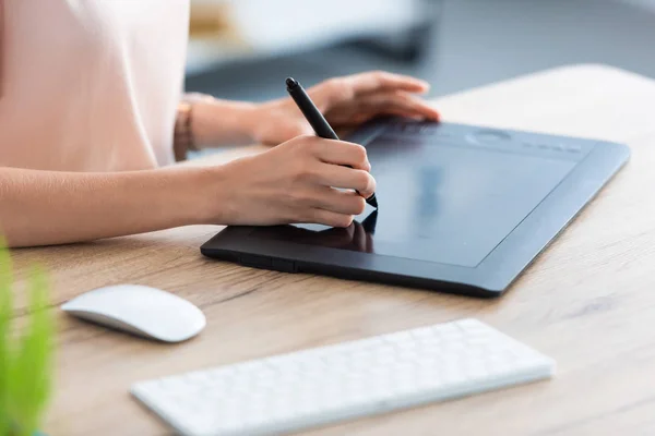 Cropped image of female freelancer drawing on graphic tablet at table in home office — Stock Photo