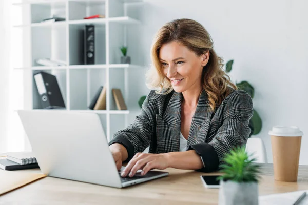 Attractive businesswoman working on laptop in office — Stock Photo