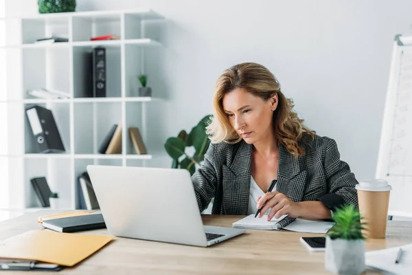 Schöne Geschäftsfrau mit Laptop und Notizbuch im Büro — Stockfoto