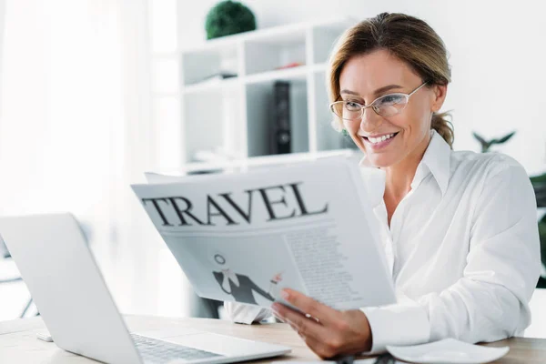 Attraktive Geschäftsfrau liest im Büro Reisezeitung — Stockfoto