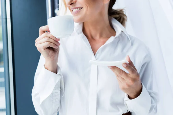 Geschnittenes Bild einer Geschäftsfrau mit einer Tasse Kaffee im Büro — Stockfoto