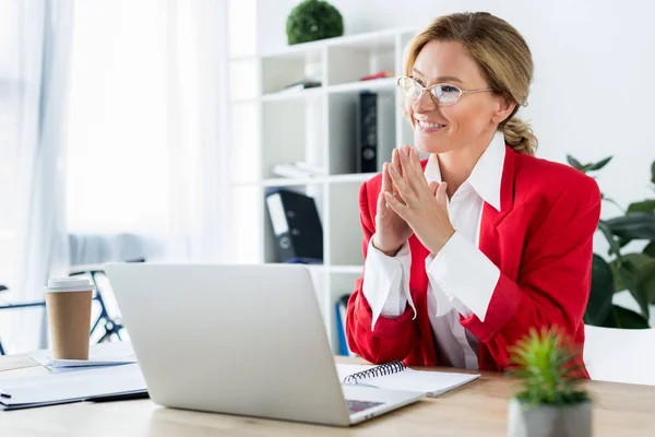 Felice donna d'affari attraente seduta a tavola con computer portatile in ufficio — Foto stock