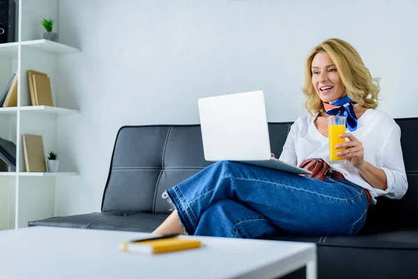 Приваблива бізнес-леді, що працює з ноутбуком в офісі і тримає склянку соку — стокове фото