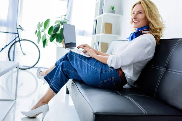 Боковой вид привлекательной бизнесвумен, работающей с ноутбуком в офисе — стоковое фото