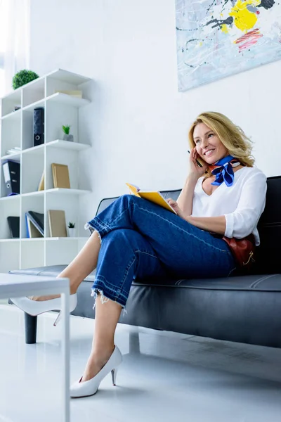 Attraktive Geschäftsfrau sitzt mit Notizbuch auf Sofa im Büro — Stockfoto