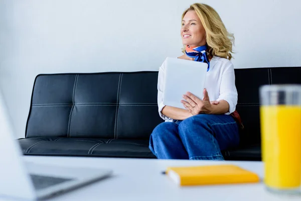 Усміхнена приваблива бізнес-леді тримає планшет і дивиться в офіс — стокове фото