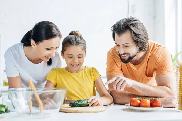 Happy young family cooking healthy dinner together at kitchen — Stock Photo