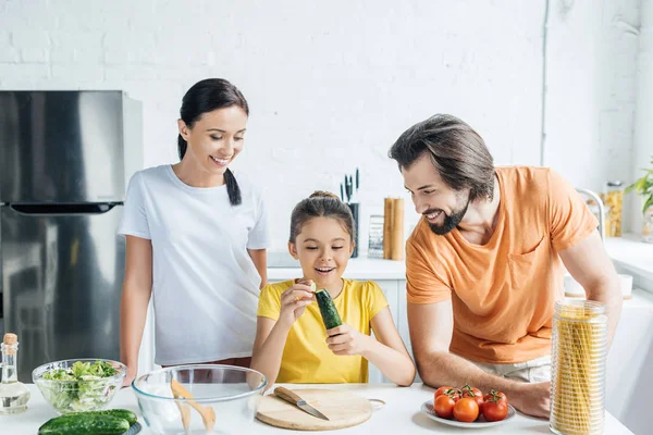 Beautiful young family cooking healthy dinner together at kitchen — Stock Photo