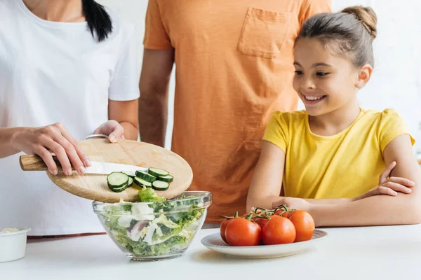 Tiro cortado de família jovem preparando salada na cozinha — Fotografia de Stock