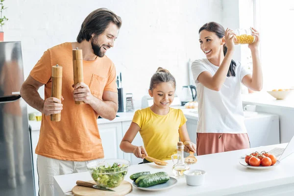 Bela jovem família tocando música com utensílios de cozinha e se divertindo na cozinha — Fotografia de Stock