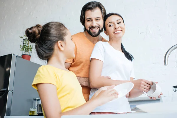 Schöne junge Familie spült gemeinsam Geschirr in der Küche — Stockfoto