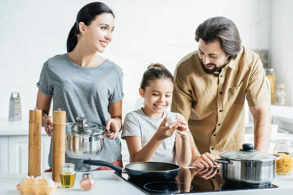 Famille souriante avec petite fille cuisine omelette à la cuisine — Photo de stock