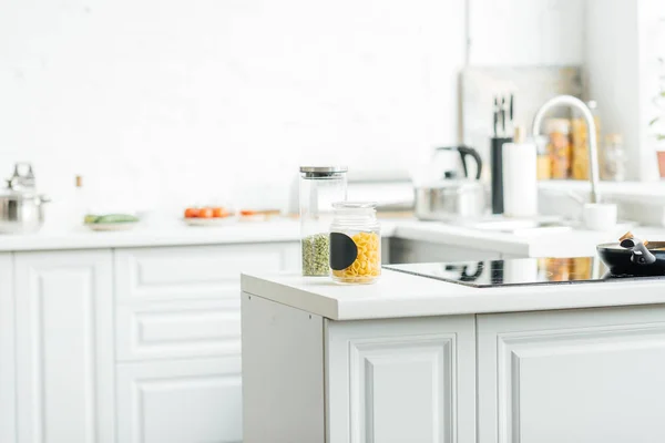 Интерьер пустой современной белой кухни с банками на столе — стоковое фото