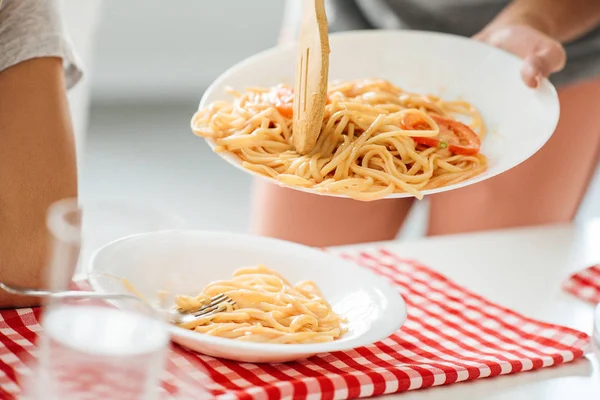 Tiro recortado de la mujer que sirve deliciosa pasta en el plato - foto de stock