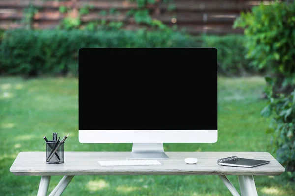 Enfoque selectivo de la computadora en la mesa con libro de texto al aire libre - foto de stock