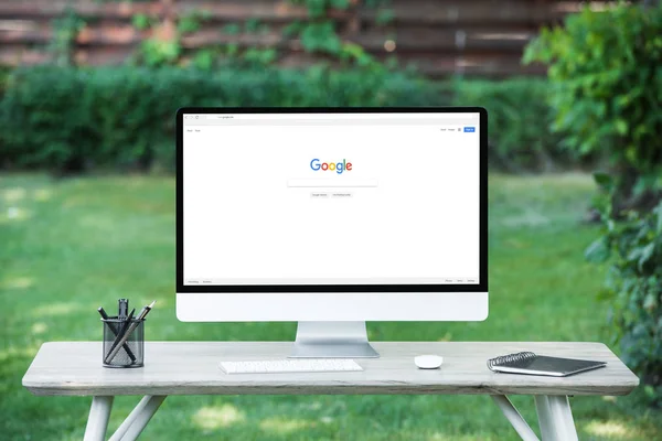 Enfoque selectivo de la computadora con el sitio web de Google en la mesa al aire libre - foto de stock