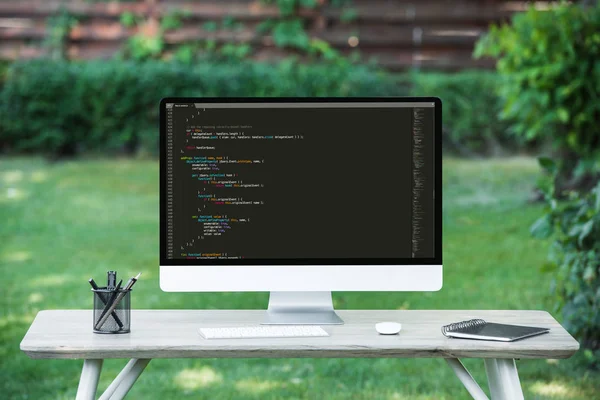 Selective focus of computer monitor with  programming language code at table outdoors — Stock Photo
