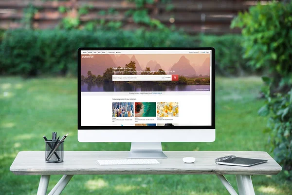 Enfoque selectivo de la computadora con obturador sitio web en la mesa al aire libre - foto de stock