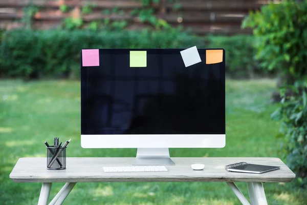 Selective focus of computer monitor with blank screen and stick it notes at table outdoors — Stock Photo