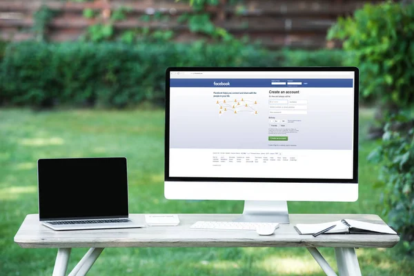 Selective focus of laptop with blank screen computer with facebook website at table outdoors — Stock Photo