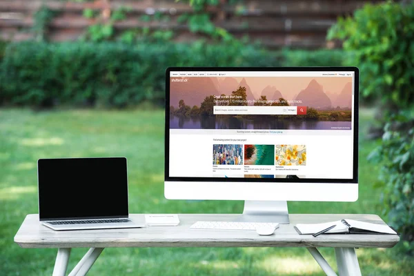 Selective focus of laptop with blank screen computer with shutterstock website at table outdoors — Stock Photo