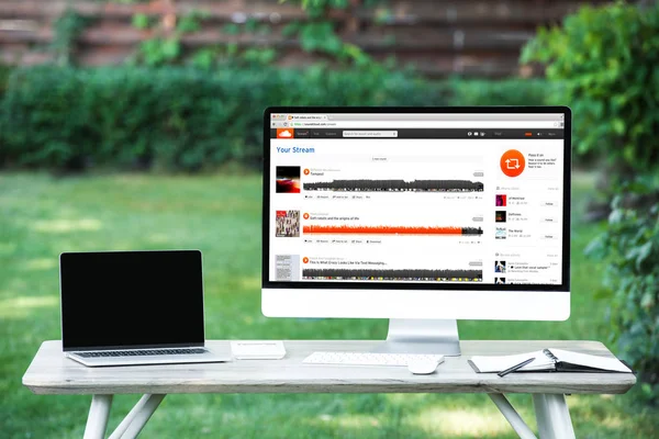 Messa a fuoco selettiva del computer portatile con schermo bianco con sito web soundcloud a tavola all'aperto — Foto stock