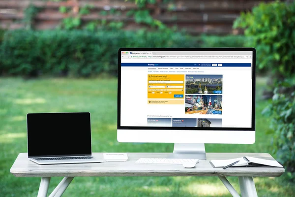 Selective focus of laptop with blank screen computer with booking.com website at table outdoors — Stock Photo