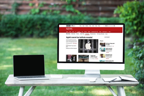 Enfoque selectivo de la computadora portátil con computadora de pantalla en blanco con el sitio web de noticias de la penes en la mesa al aire libre - foto de stock