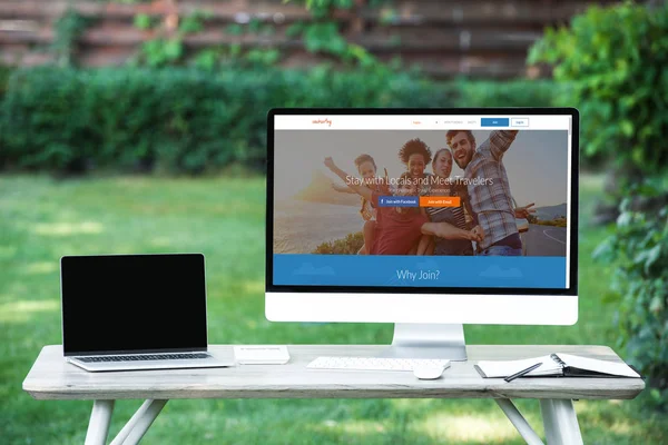 Selective focus of laptop with blank screen computer with couchsurfing website at table outdoors — Stock Photo