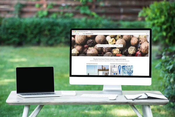 Selective focus of laptop with blank screen computer with depositphotos.com website at table outdoors — Stock Photo