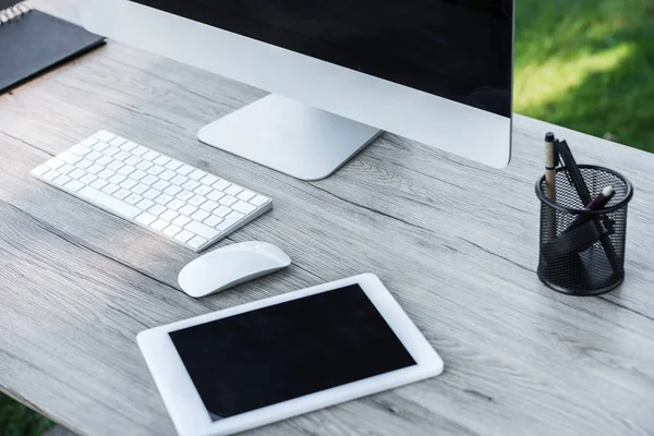 Selective focus of digital tablet and computer with blank screens at table outdoors — Stock Photo