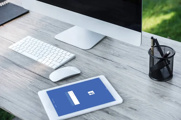 Foco seletivo de tablet digital com site facebook e computador com tela em branco à mesa ao ar livre — Fotografia de Stock