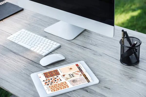 Selective focus of digital tablet with pinterest website and computer with blank screen at table outdoors — Stock Photo