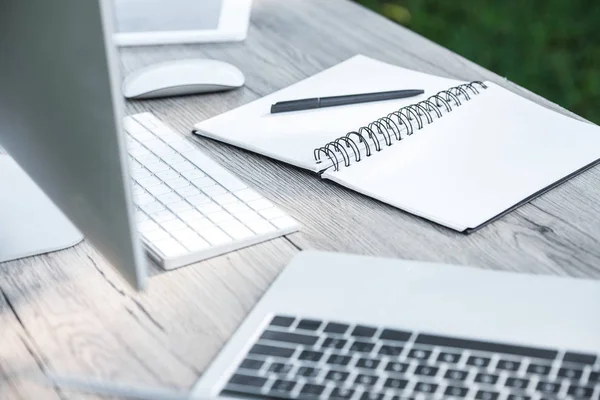 Selective focus of empty textbook with pen, laptop, digital tablet and computer on table outdoors — Stock Photo